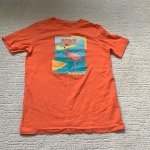 An orange Nike tee with pink flamingo.